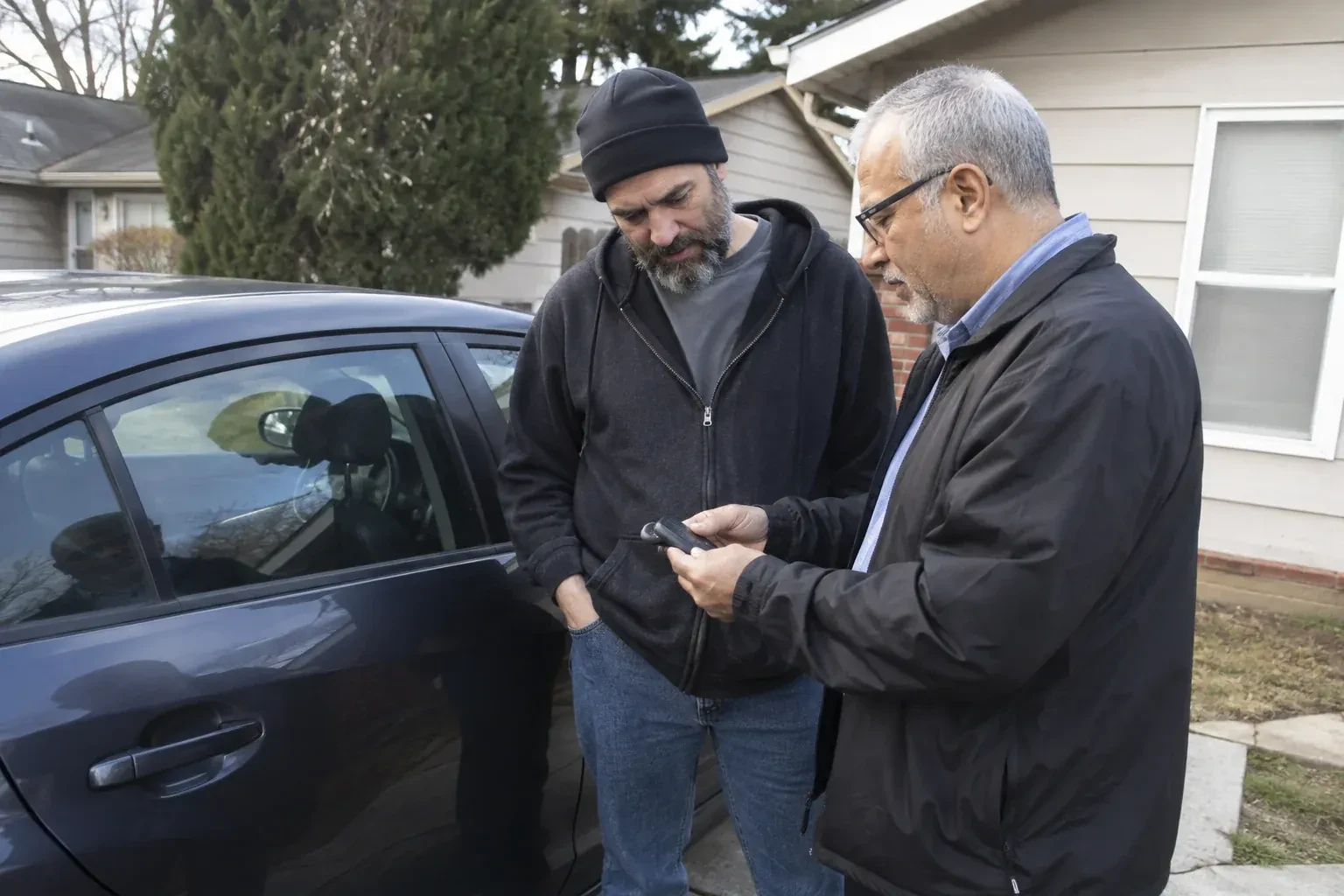 Two adults discussing a key fob beside a parked car. — Car Lockout Service, Richmond Hill